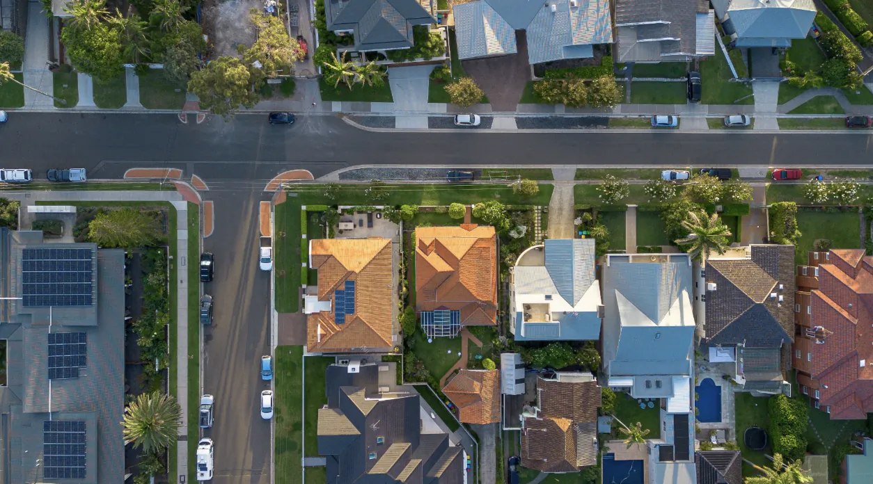 Aerial view of suburban street with houses, cars, and trees in a residential neighborhood