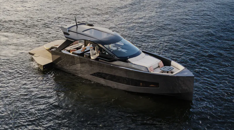 Modern dark grey yacht cruising on open water with a person visible on the deck