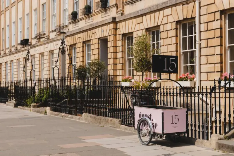 Pink GuestHouse cart marked No. 15 parked outside elegant Bath townhouse with black railings