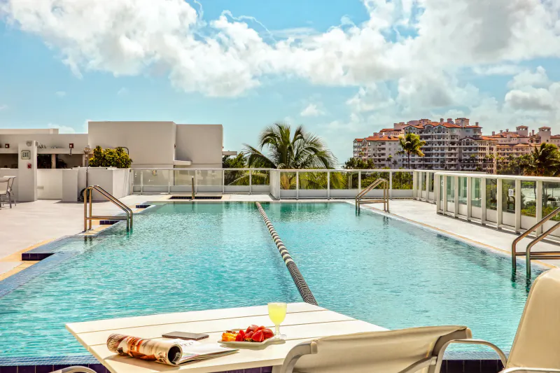 Rooftop infinity pool at Continuum Miami Beach with lounge table, fruit plate, and city skyline view