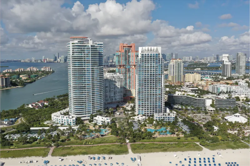 Aerial view of Continuum luxury high-rise condos on Miami Beach with oceanfront pool area, Intracoastal waterway, and downtown skyline