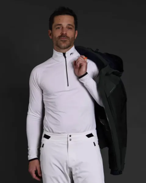 Man in white athletic top and pants holding a dark jacket over his shoulder