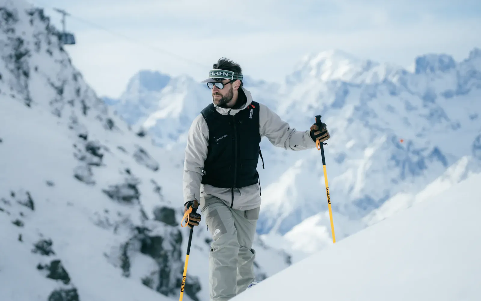 Man skiing downhill in snowy mountains wearing Vallon goggles and holding ski poles