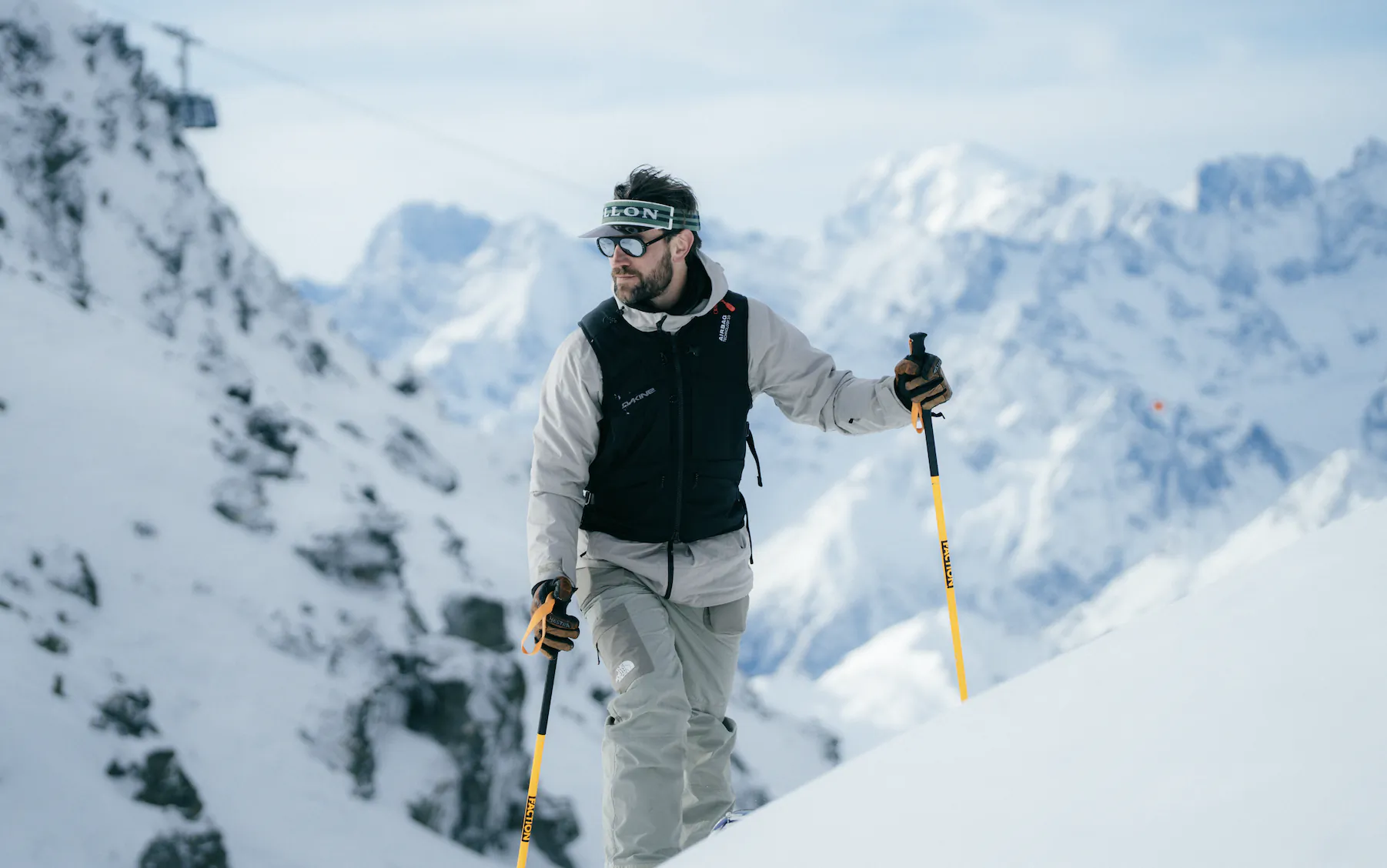 Man skiing downhill in snowy mountains wearing Vallon goggles and holding ski poles