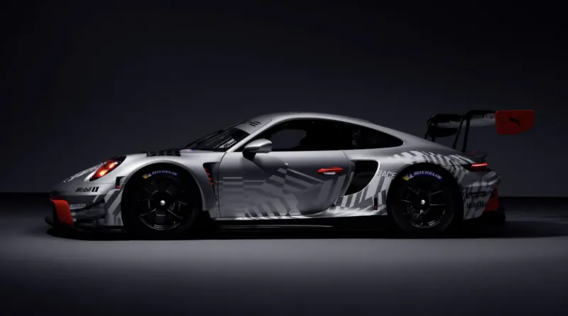 Side profile of a silver Porsche 911 race car with grey geometric decals, red accents, large rear wing, and Michelin tires