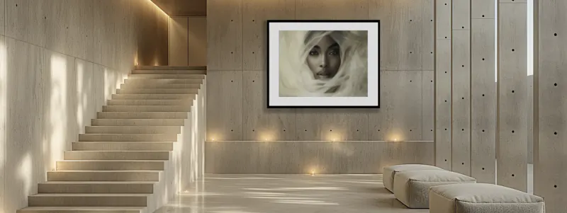 Modern minimalist hallway with concrete staircase, two white ottomans, and large framed portrait of a woman in white headscarf on wall