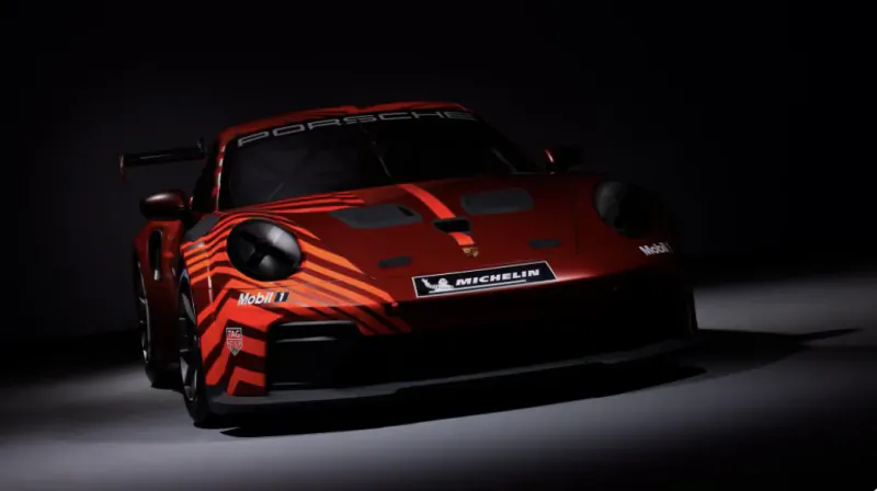 Red Porsche 911 race car with black and orange stripes in a studio setting