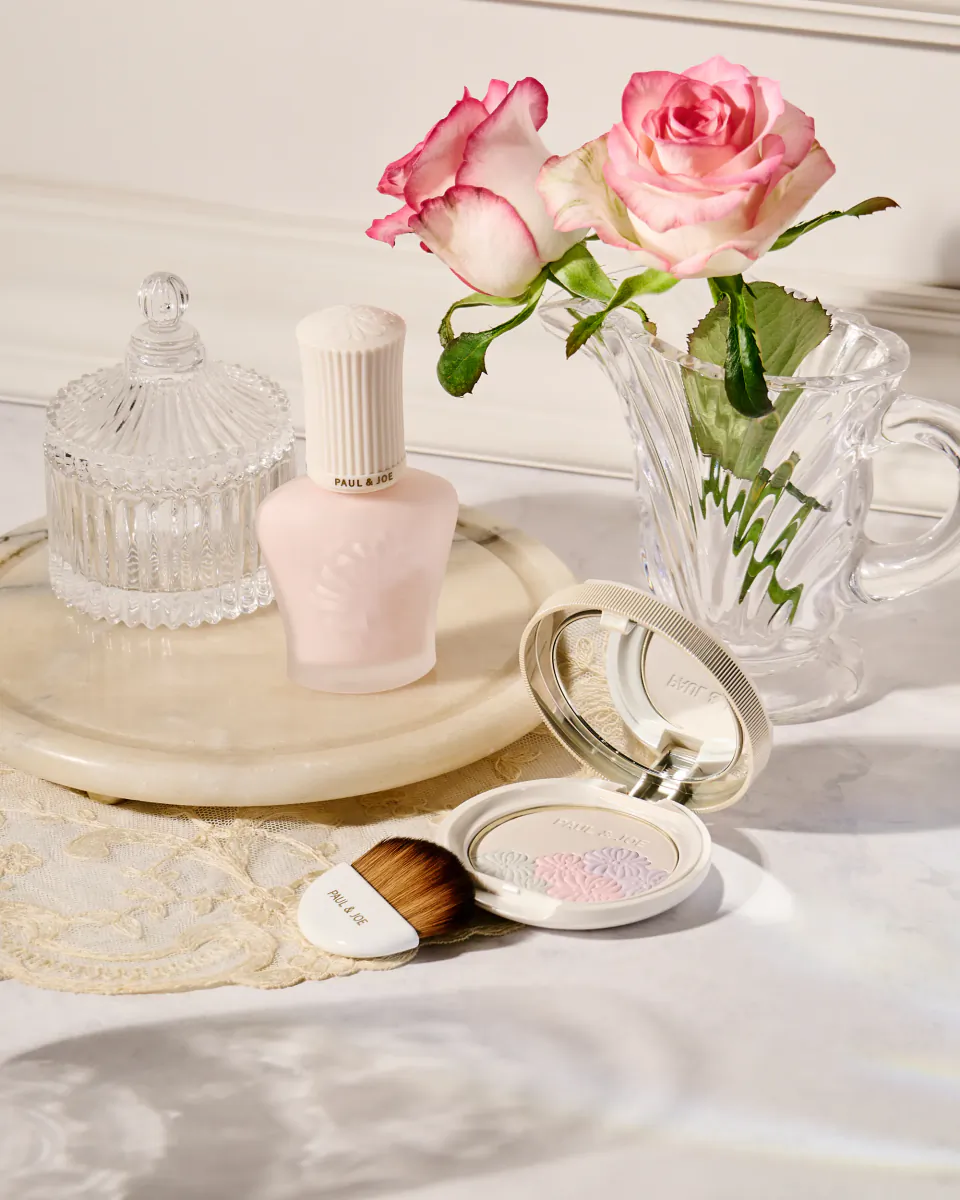Paul & Joe pink nail polish, open compact, makeup brush, pink roses in glass pitcher on marble tray