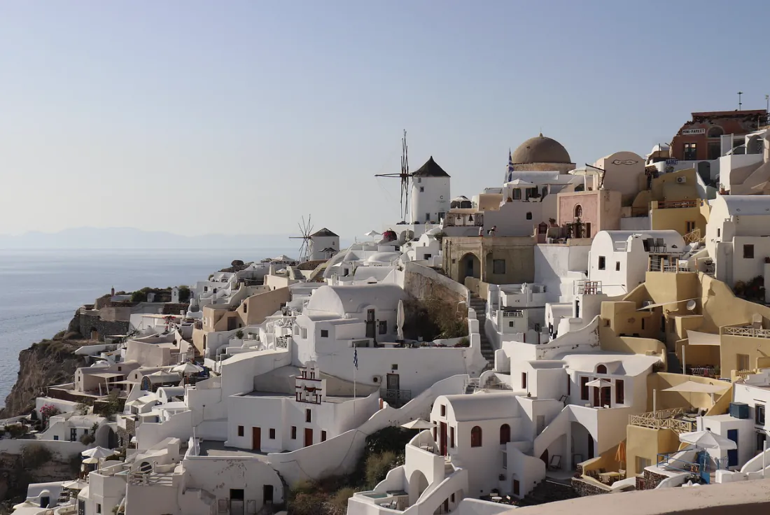 Whitewashed cliffside buildings and windmills overlooking the sea in Santorini, Greece