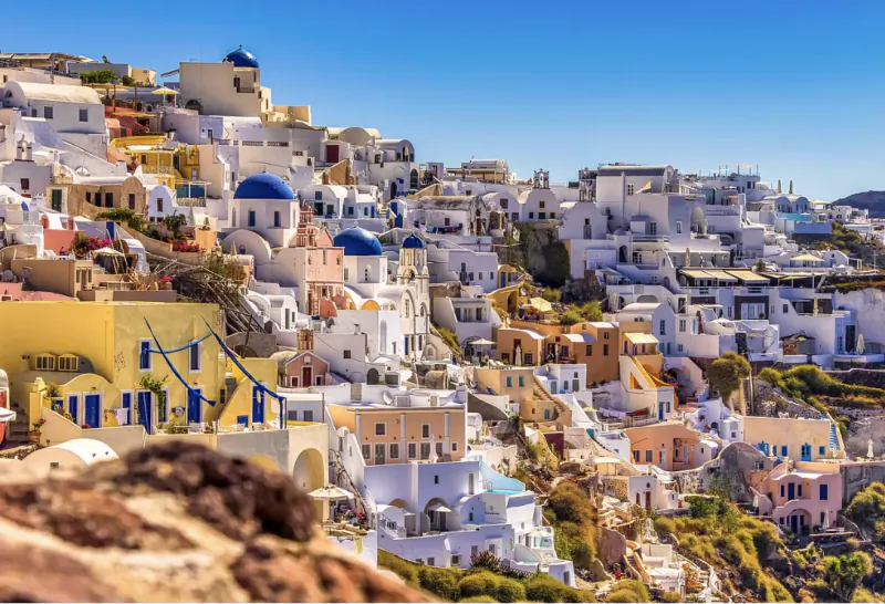Whitewashed hillside buildings with blue domes overlooking the sea in Santorini, Greece