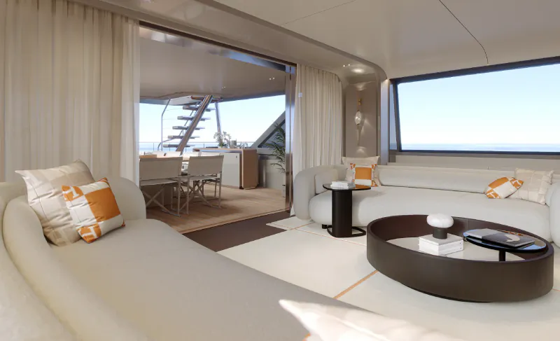 Luxury yacht salon with white sofas, orange pillows, round coffee table, and open doors to outdoor dining area