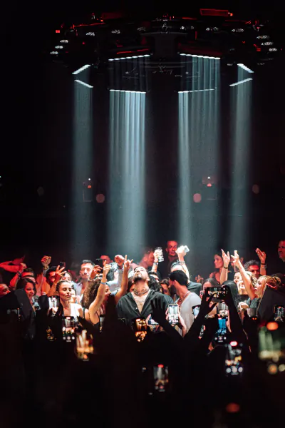 Crowd at Chinois Ibiza nightclub raising hands under dramatic overhead lights