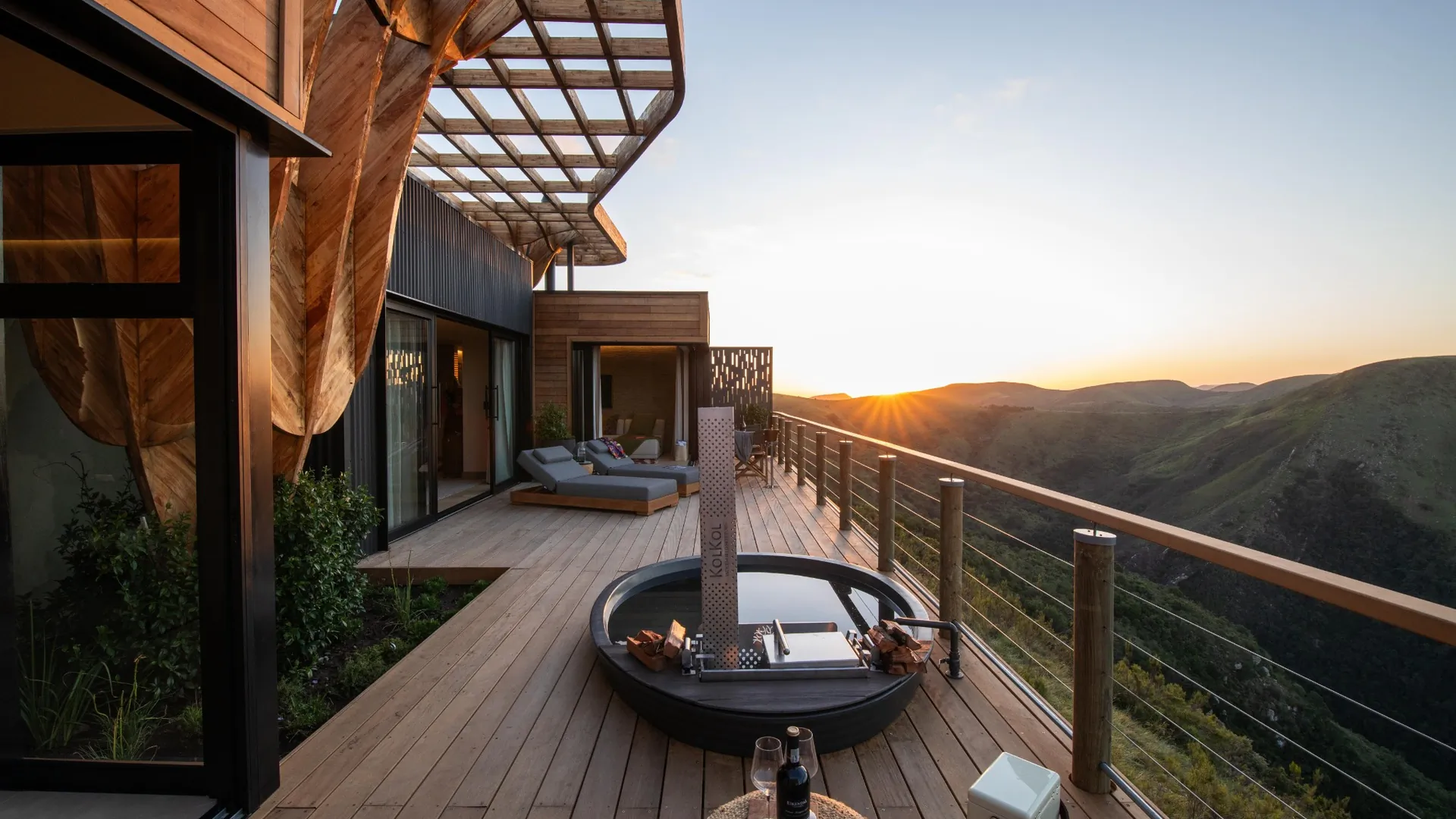 Modern wooden deck with round fire pit overlooking sunset mountain landscape at luxury South African villa