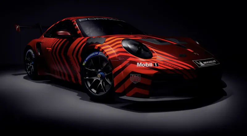 Red Porsche 911 race car with black chevron stripes and sponsor logos in studio lighting