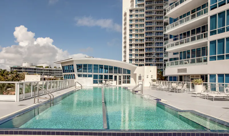 Luxury rooftop pool at Continuum Residences with modern high-rise buildings and lounge chairs
