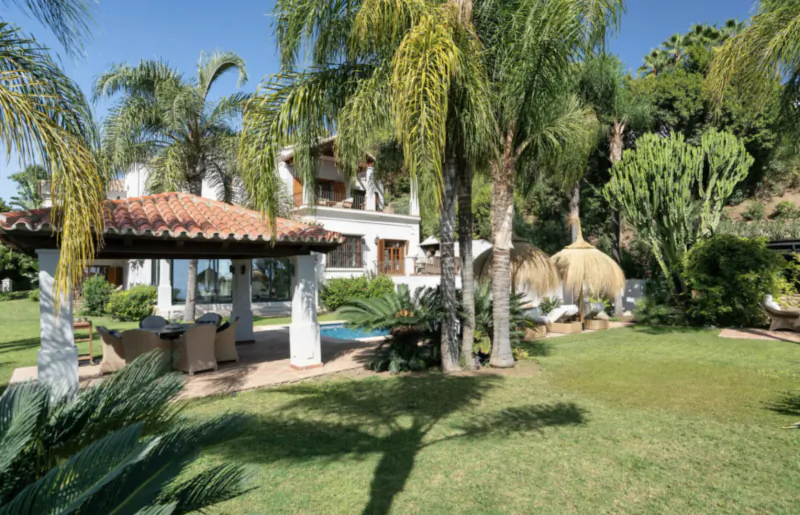 Luxury villa with pool and palm trees in Marbella garden under blue sky