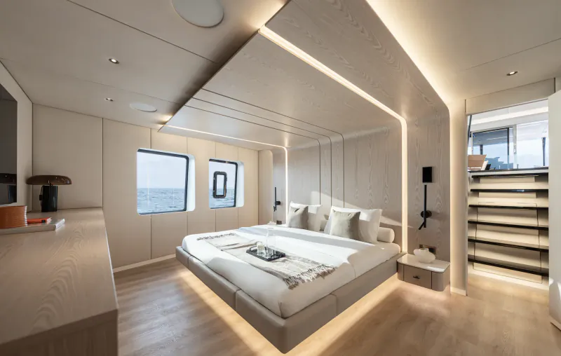 Modern yacht bedroom with floating platform bed, light wood walls, two ocean-view windows, and built-in LED lighting