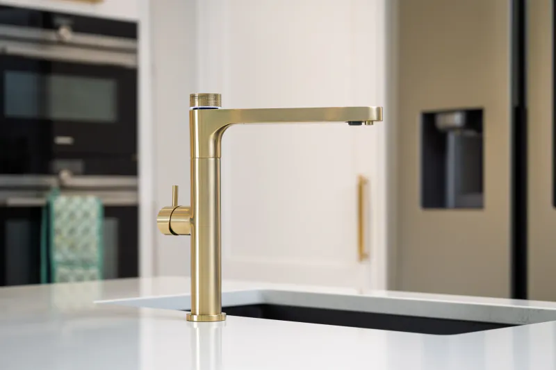 Brushed gold modern kitchen faucet with lever handle on white countertop