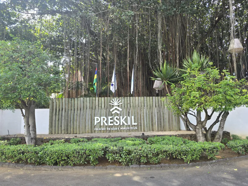 Preskil Island Resort Mauritius entrance sign with wooden fence, flags, and lush tropical greenery