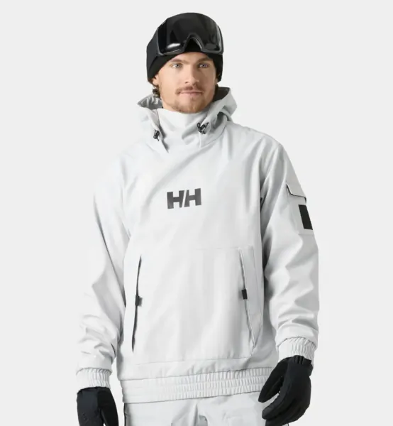 Man wearing white Helly Hansen ski jacket, black beanie and goggles, standing against white background