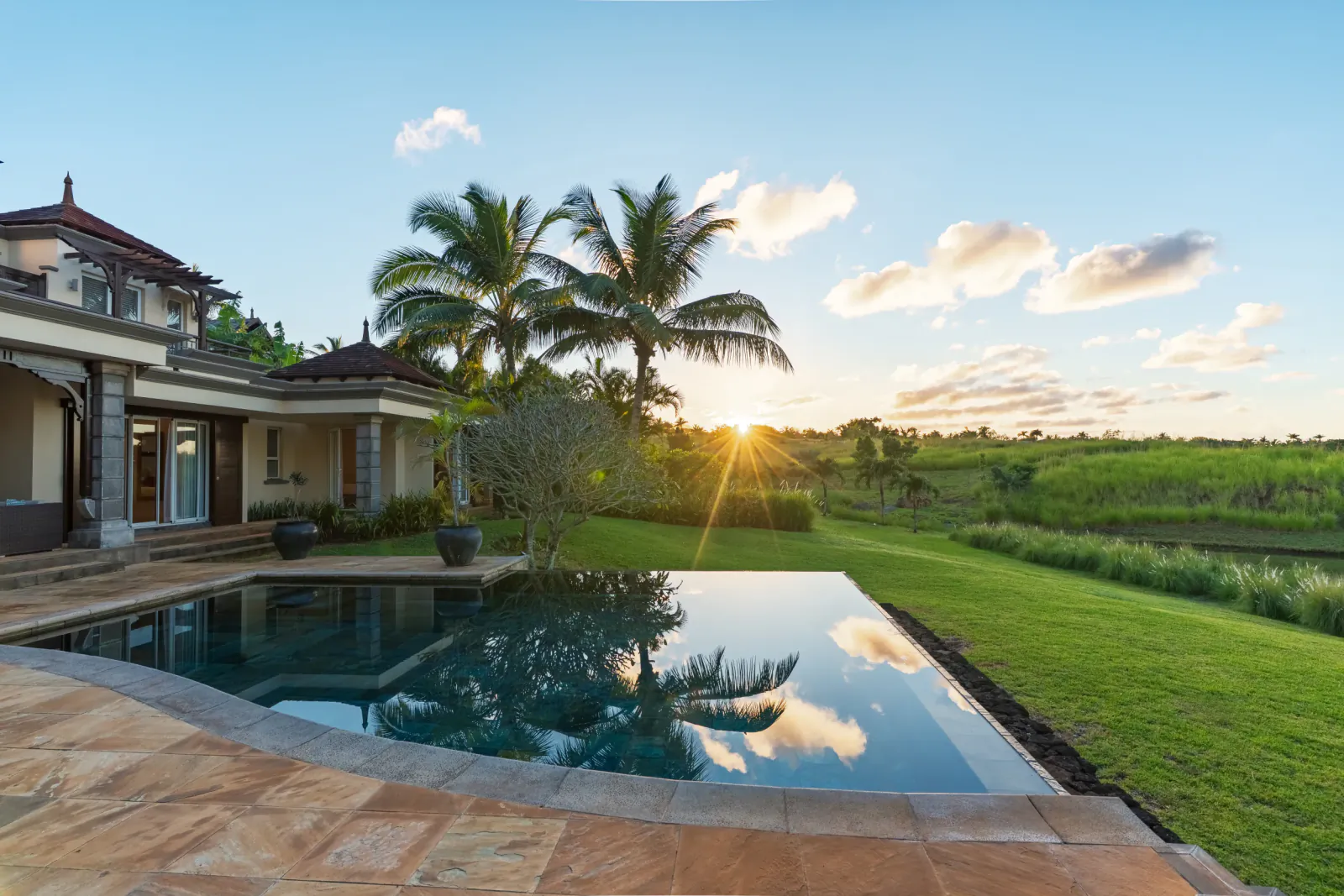Luxury villa with infinity pool overlooking green rice fields at sunset