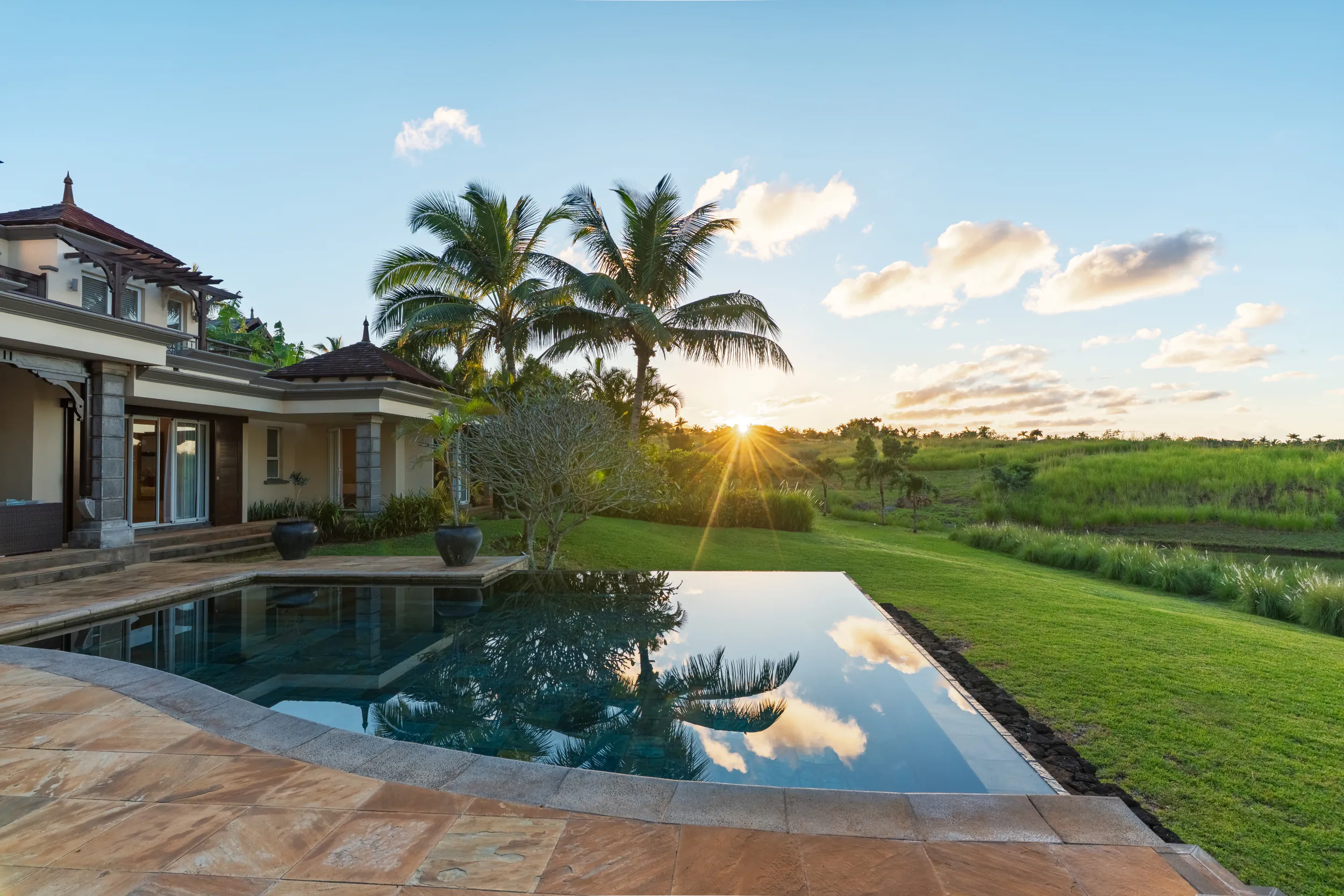 Luxury villa with infinity pool overlooking green rice fields at sunset