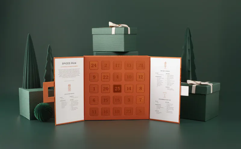 Open Master of Malt Advent Calendar with numbered doors, surrounded by green gift boxes and decorative trees on dark background
