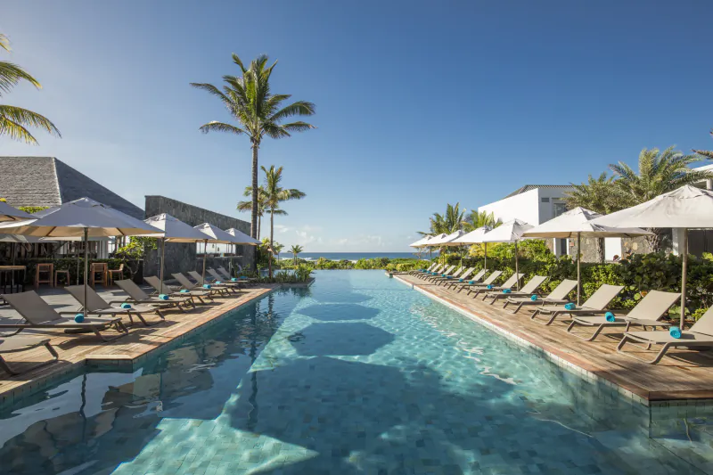 Luxury resort infinity pool with lounge chairs and umbrellas overlooking the ocean in Mauritius