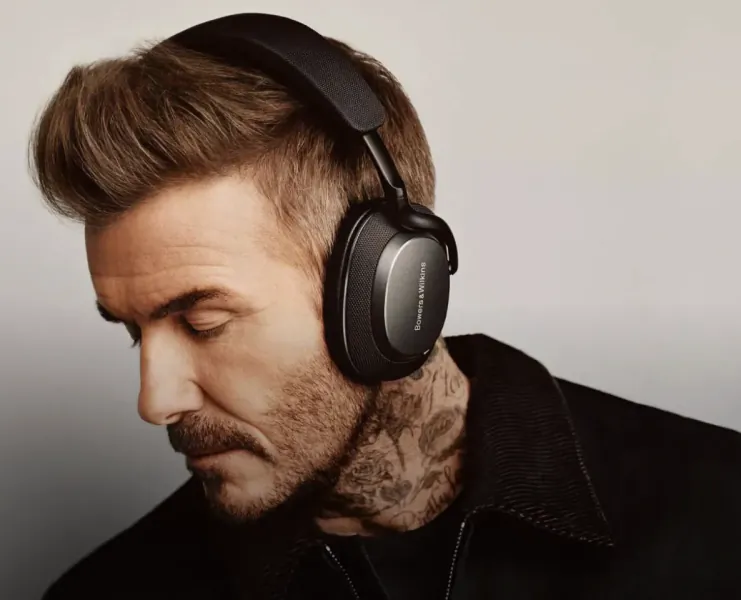 David Beckham wearing black Bowers & Wilkins headphones, eyes closed, head tilted down