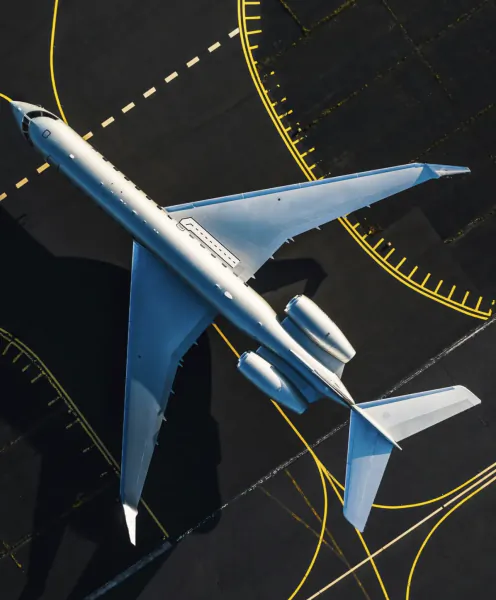 White private jet parked on dark tarmac with yellow markings