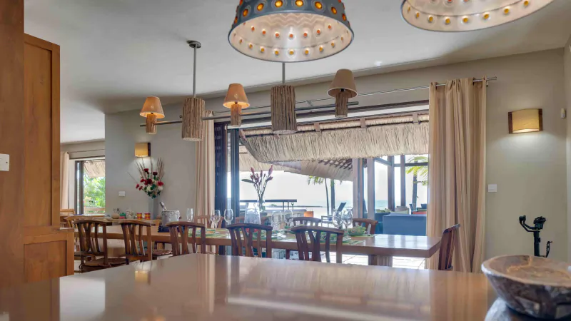 Modern dining room with wooden table, chairs, and decorative pendant lights overlooking a balcony