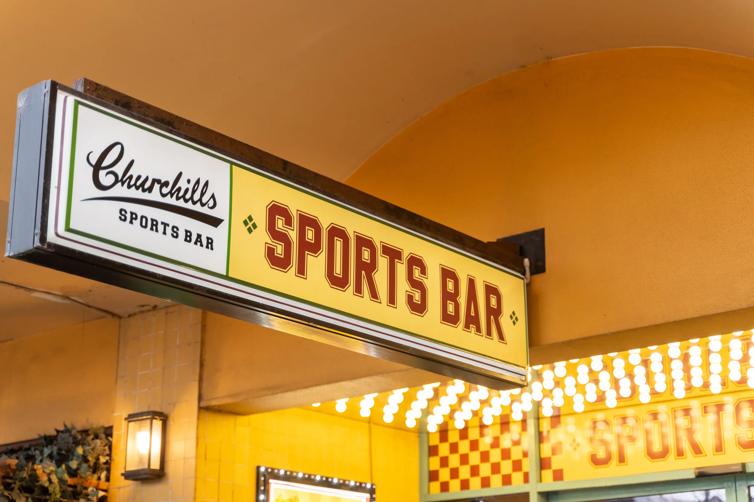 Churchill's Sports Bar illuminated sign with red and yellow lettering on a building facade
