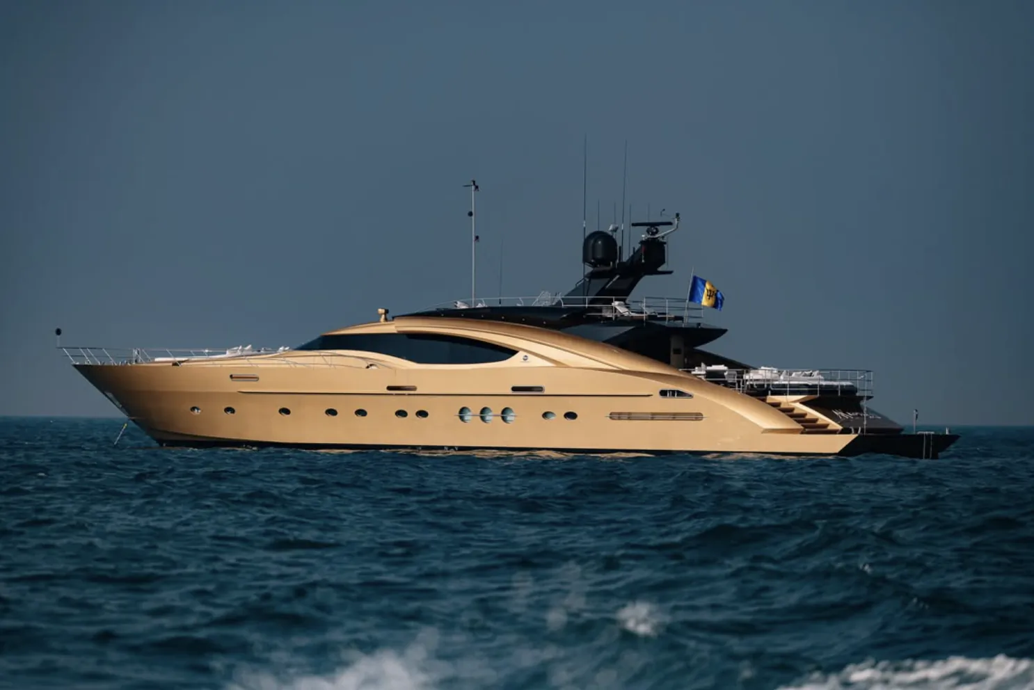 Luxury beige yacht cruising on open blue sea under clear sky