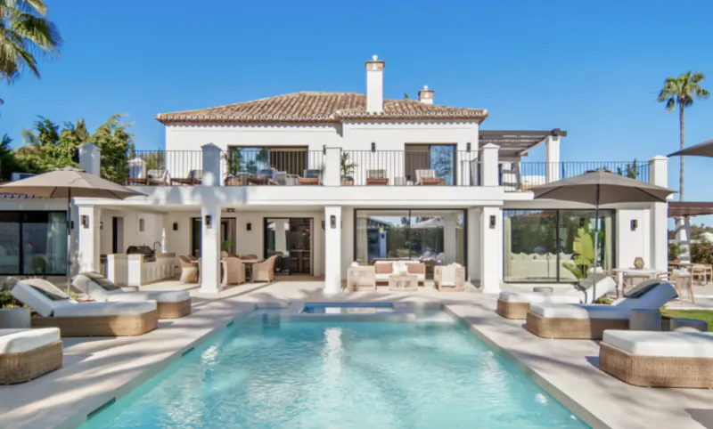 Luxury white villa with pool, sun loungers, and terrace overlooking the sea in Marbella