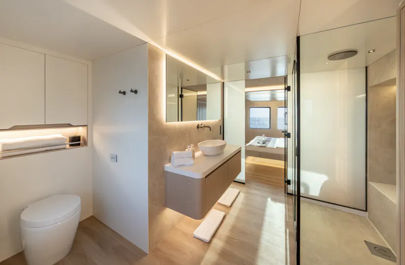 Modern yacht bathroom with floating vanity, backlit mirror, wall-mounted toilet, and glass shower enclosure