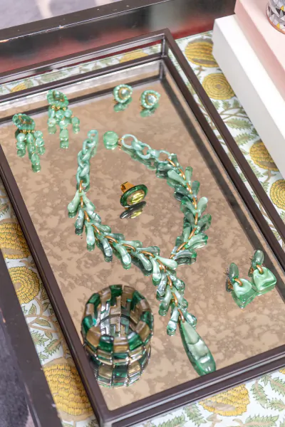 Green glass and gold jewelry set including necklace, earrings, ring, and bracelet displayed on a mirrored tray