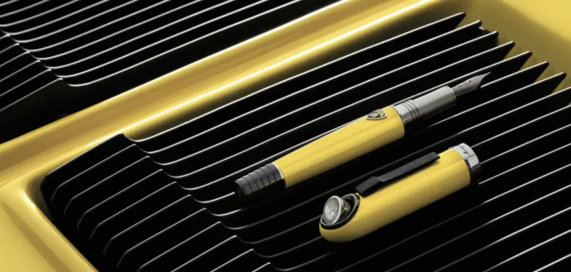 Yellow luxury fountain pen and matching cap on black ribbed surface with yellow accents
