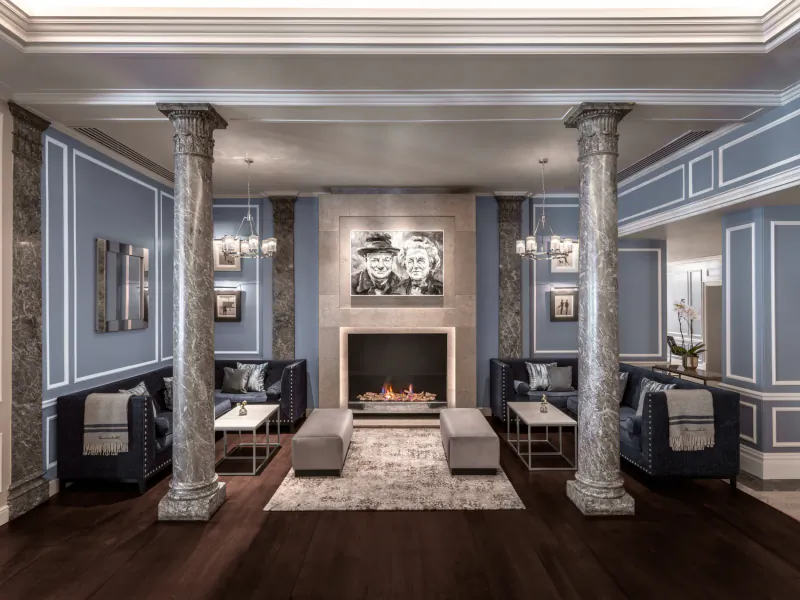 Luxurious hotel lounge with marble columns, blue walls, fireplace, and black sofas