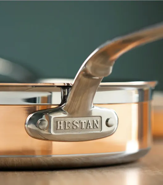 Close-up of Hestan stainless steel pan handle with embossed logo on copper cookware