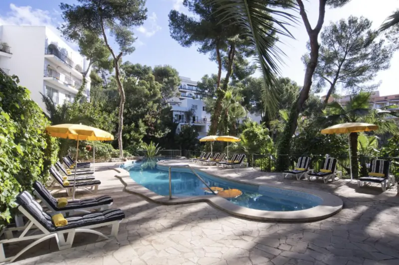 Hotel pool area with lounge chairs, yellow umbrellas, and palm trees on a sunny day