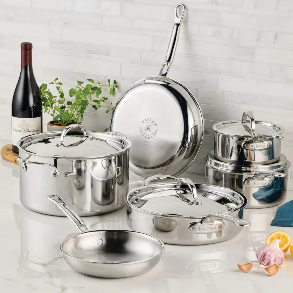 Hestan ProBond Luxe 10-piece stainless steel cookware set with pots, pans, and lids on marble countertop