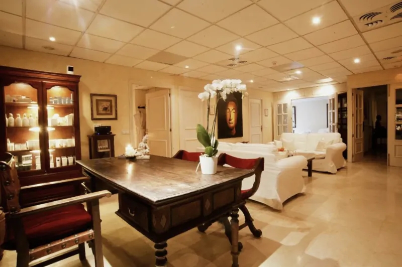 Elegant hotel lounge with dark wood table, red velvet chairs, white sofas, and large orchid arrangement