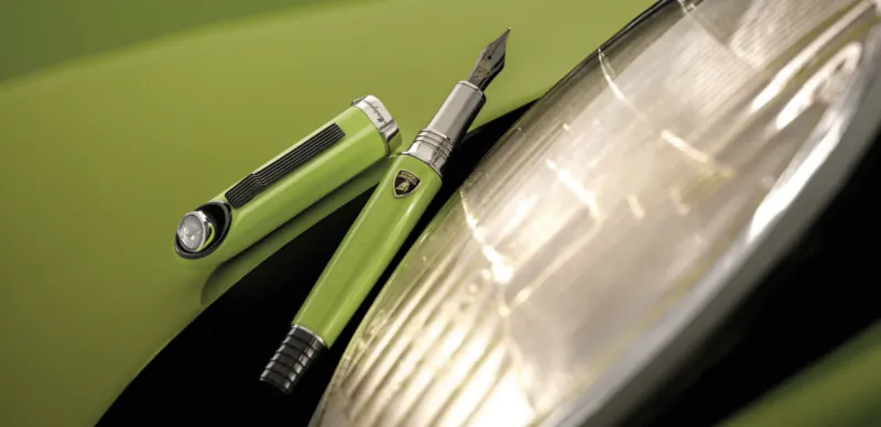 Green Lamborghini and Montegrappa fountain pen on lime green car hood beside headlight