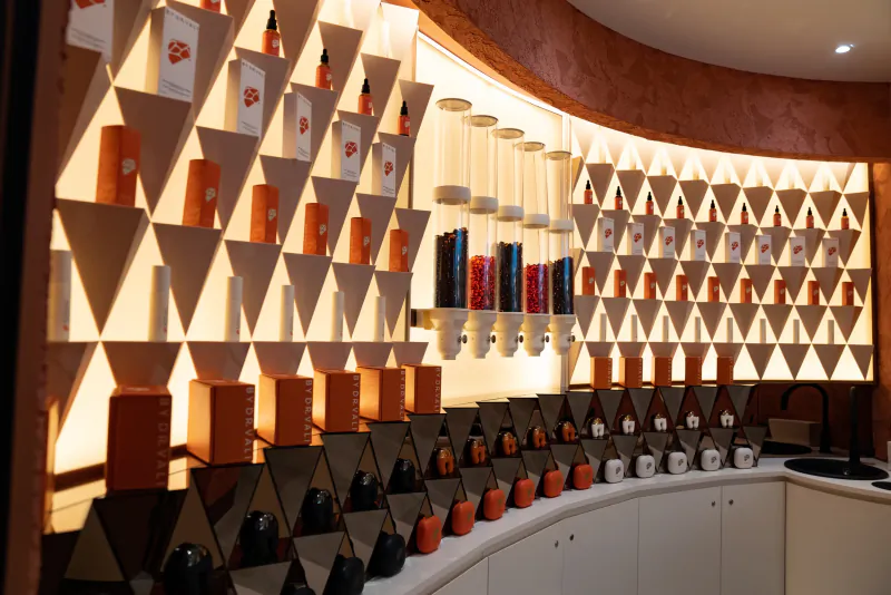 Modern skincare store interior with illuminated geometric wall displays of orange and black product bottles and boxes